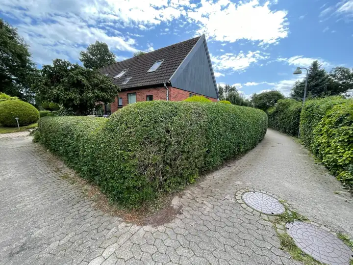 Afrundet klippet hæk ved et hus på et hjørne